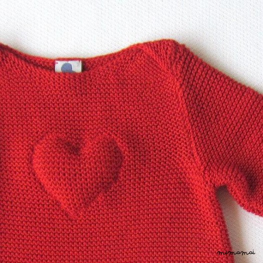 Un abito di maglia bambino in rosso con un cuore. 100% cotone.